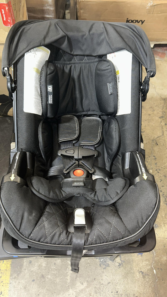 Black baby car seat with straps on a concrete floor