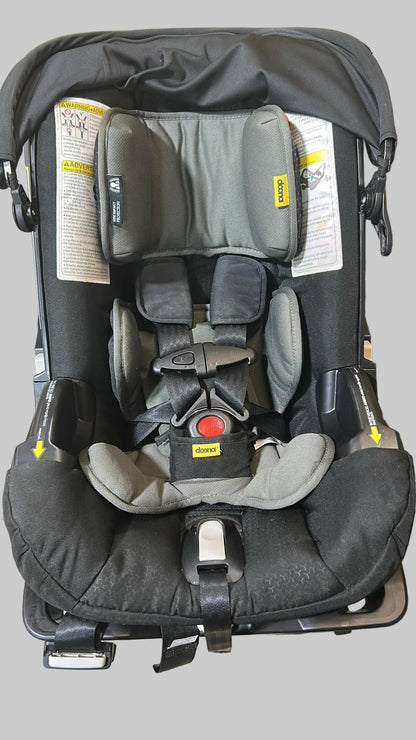 Black and gray car seat with visible branding on a concrete floor.
